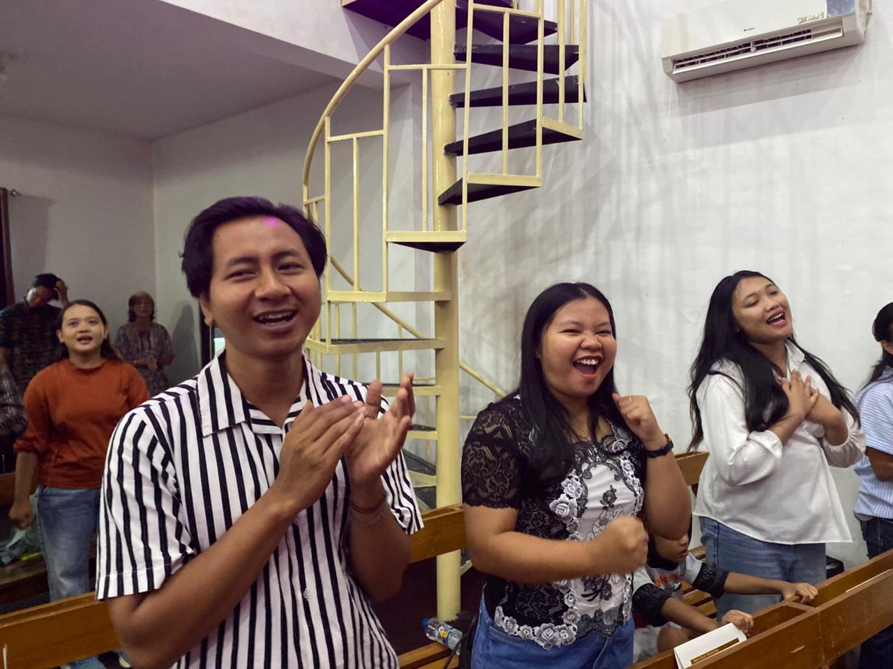 Three friends clapping and cheering mid-laugh during a service at Cemani