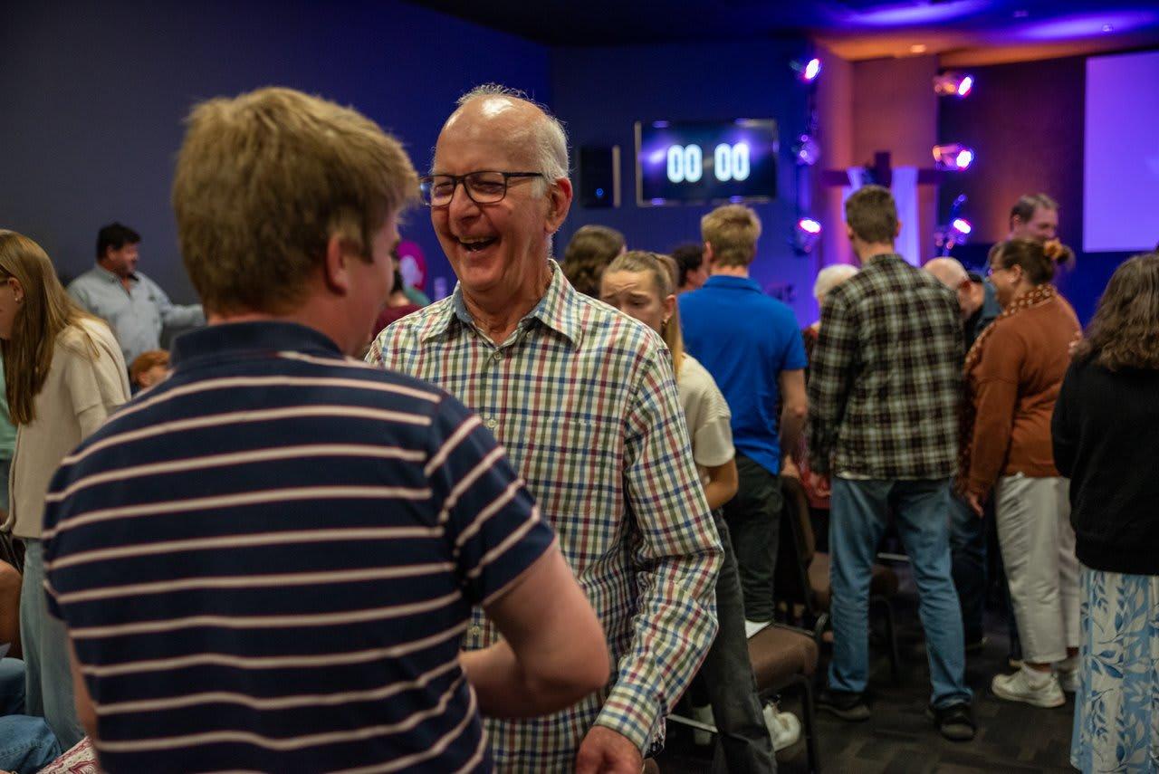 A man mid-belly-laugh in conversation after the service