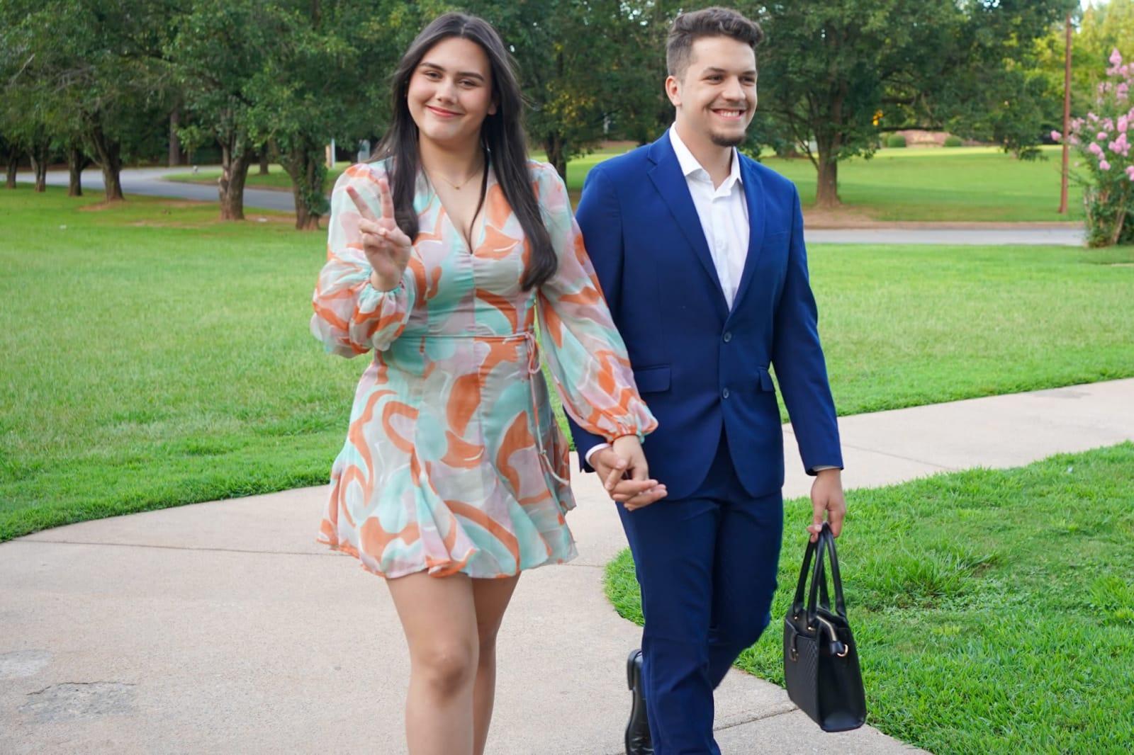 A couple in their Sunday best walking in hand in hand, grinning