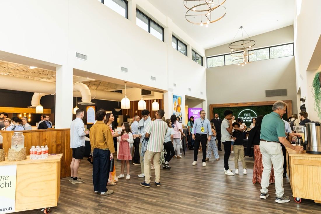 A bright, multigenerational and multicultural crowd mingling in the airy foyer at Futures Alpharetta