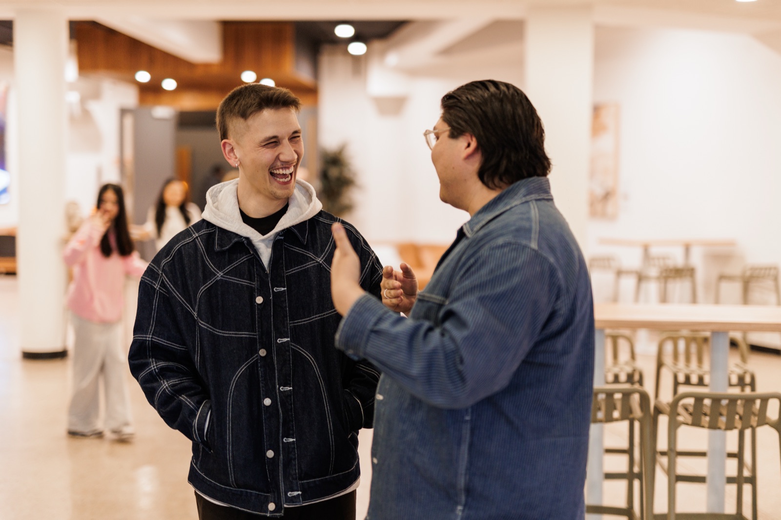Two guys laughing together in the bright food court at Futures Alpharetta