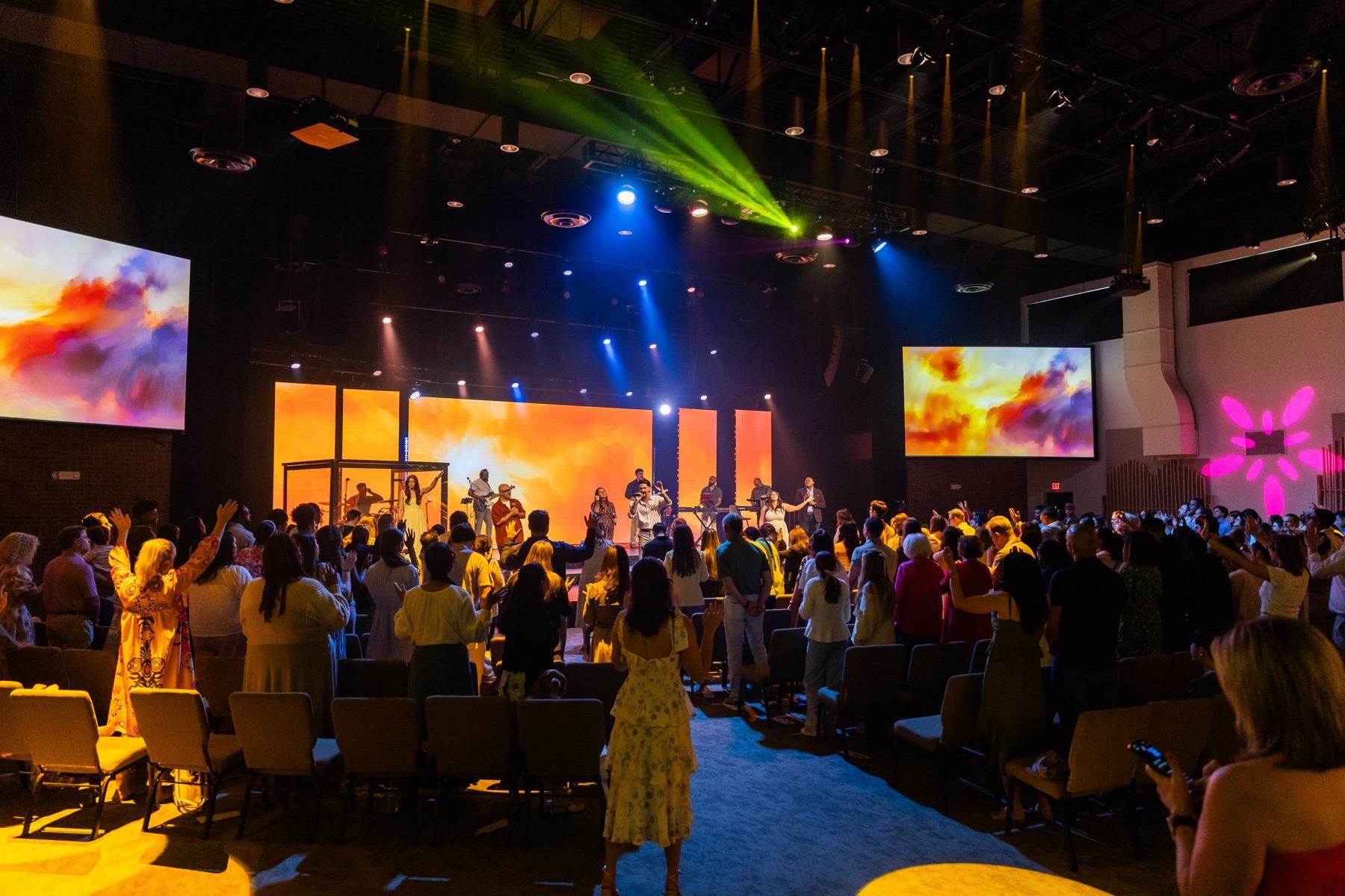 A full, diverse room worshipping together with hands raised at Futures Alpharetta
