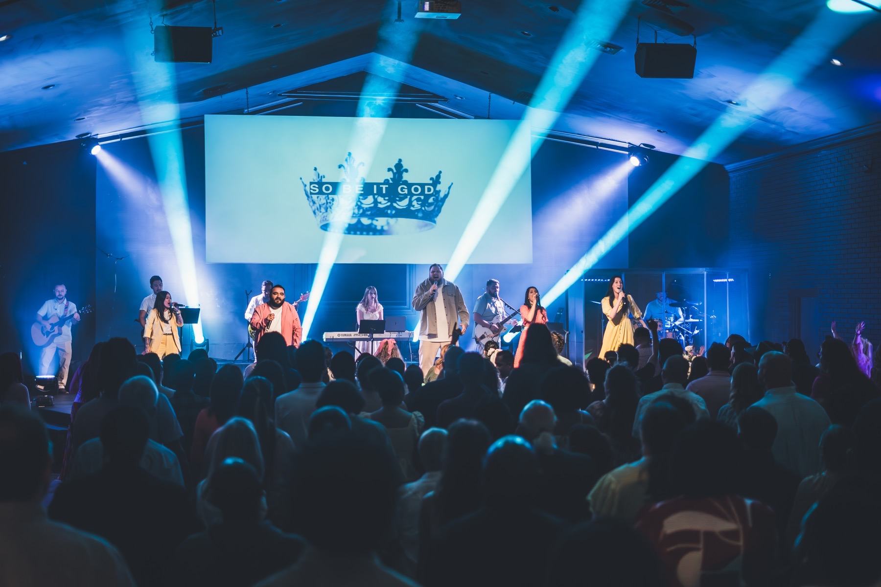 A full, diverse room worshipping together under blue light at Futures Kennesaw